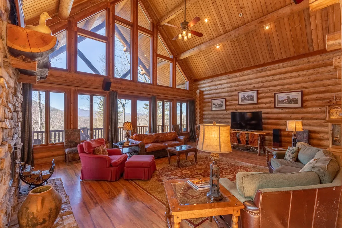A warm, spacious living area with large windows offering scenic views, a stone fireplace, comfortable seating, and wooden beams. The space is ideal for families and small pets to unwind after a day of exploring.